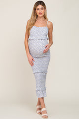 woman wearing a light blue floral maternity dress with ruffles and a visible baby bump