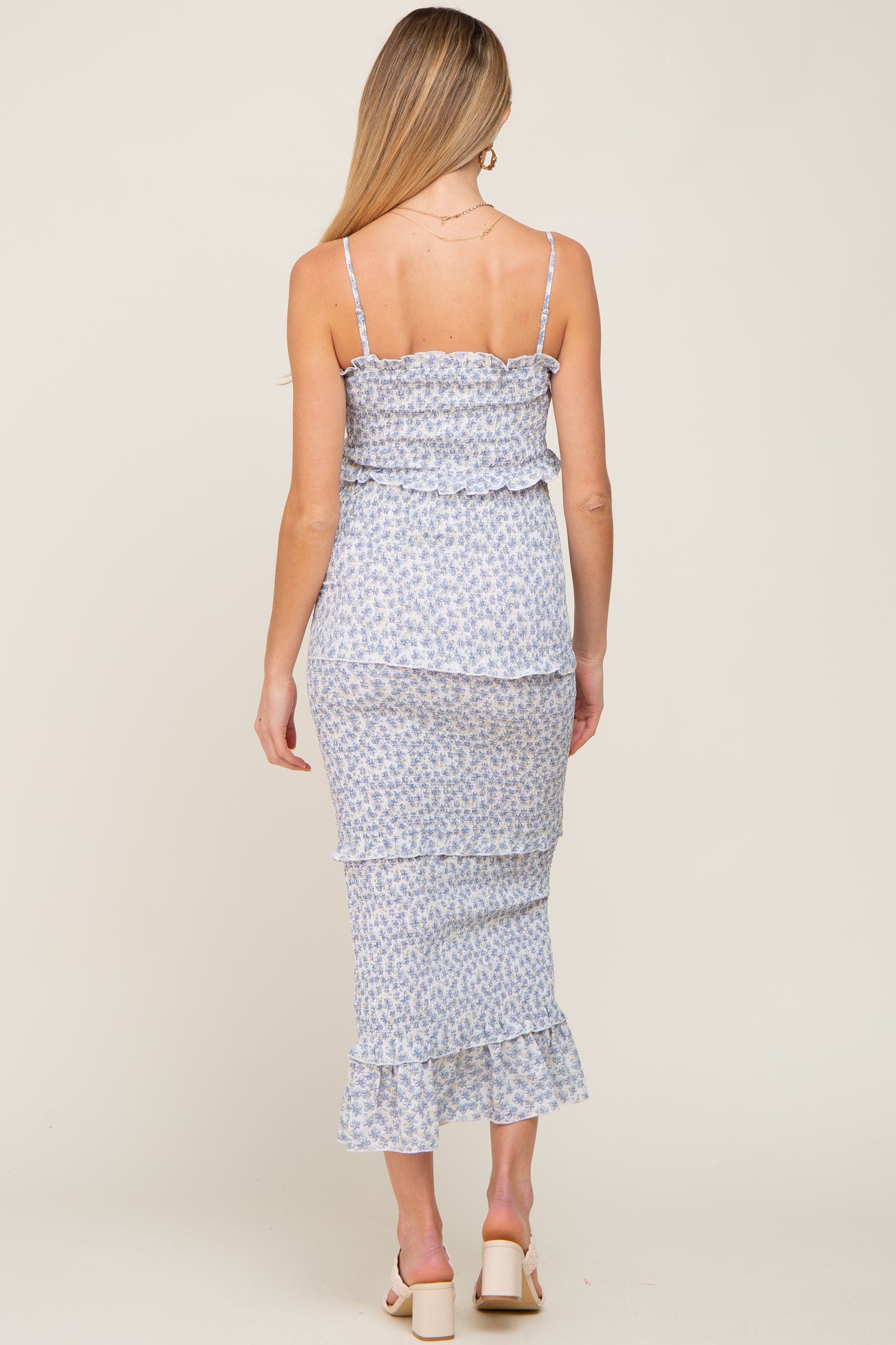 woman wearing a light blue floral maternity dress with ruffle hem and adjustable spaghetti straps, seen from the back