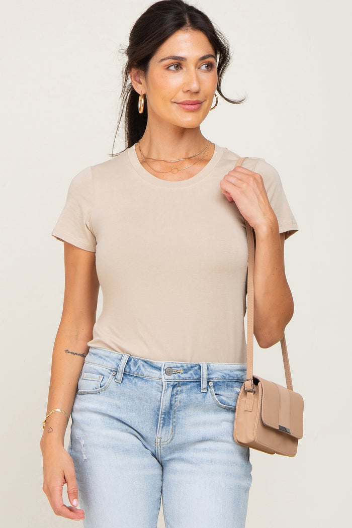 woman wearing a beige short sleeve t-shirt and light wash denim jeans with a matching crossbody bag