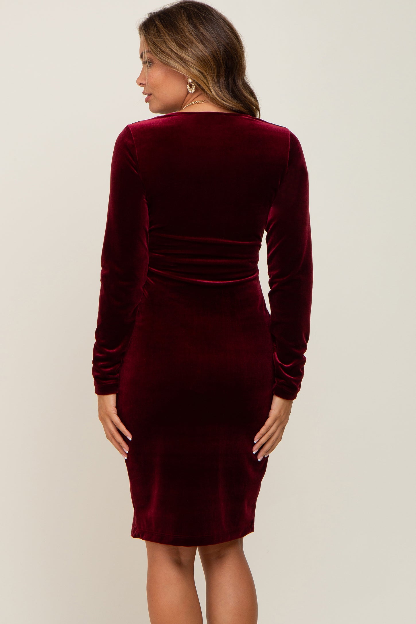 woman wearing a burgundy long sleeve maternity dress with a fitted silhouette and soft velvet fabric