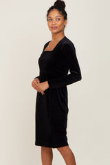 woman wearing a black velvet long sleeve dress with a square neckline and a fitted silhouette
