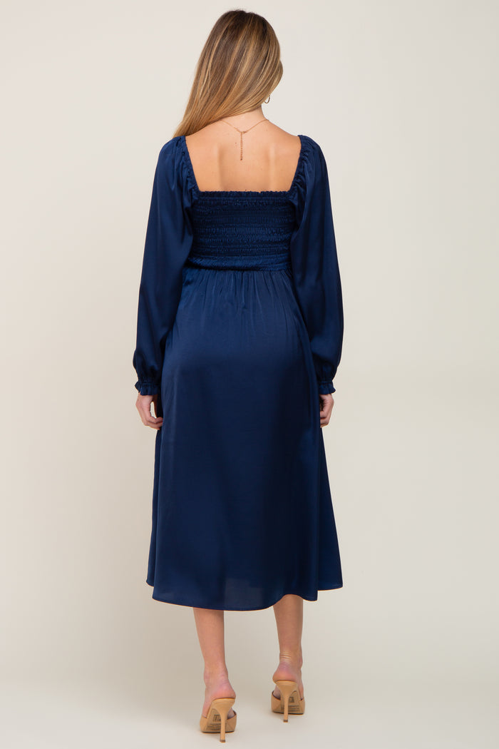 woman wearing a navy blue maternity dress with a smocked bodice and long sleeves seen from the back