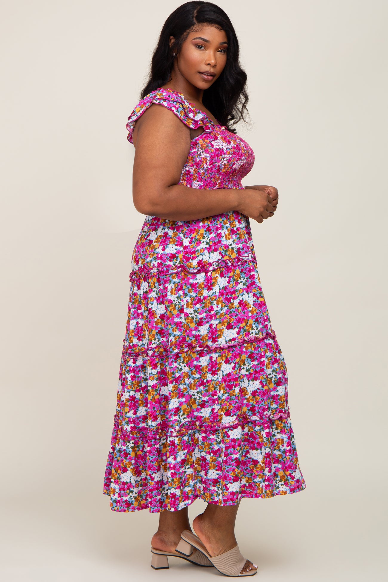 woman wearing a floral plus-size maxi dress with ruffled straps and a tiered skirt