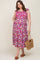 woman wearing a floral maternity plus dress with ruffled sleeves and holding a straw bag, baby bump visible
