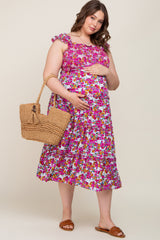 woman wearing a floral maternity plus dress with ruffle details and holding her baby bump, carrying a woven bag