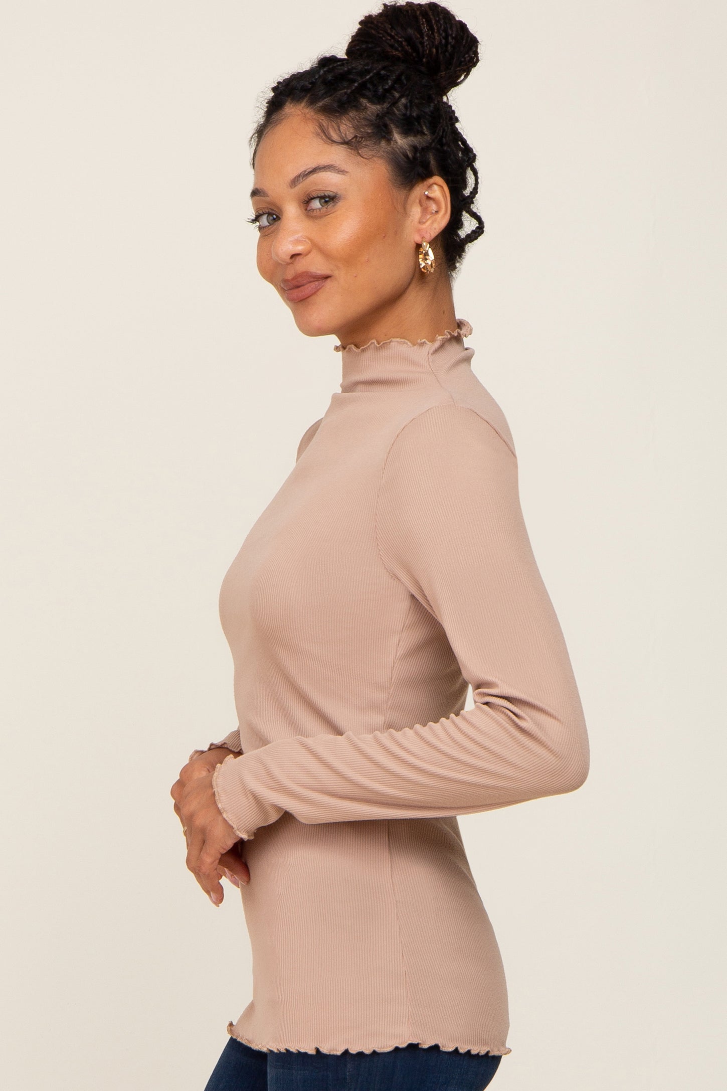 woman wearing a light brown long sleeve top with ruffled neckline and cuffs