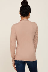 woman wearing a ribbed nude long sleeve top with a ruffled collar, viewed from the back
