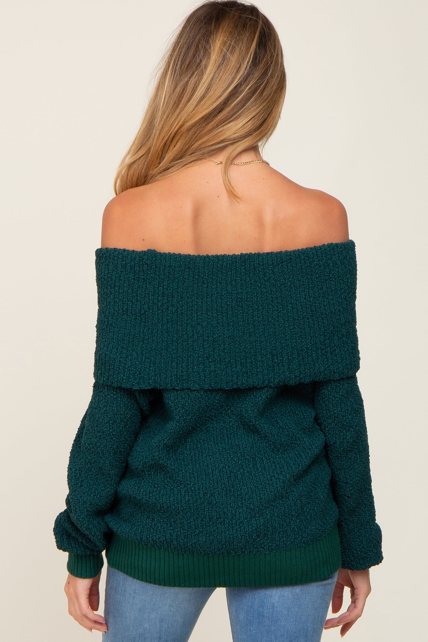 woman wearing a dark green off-the-shoulder maternity sweater with a relaxed fit, shown from the back