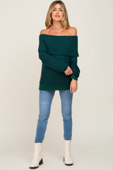 woman wearing a dark green off-the-shoulder maternity sweater paired with skinny jeans and ankle boots