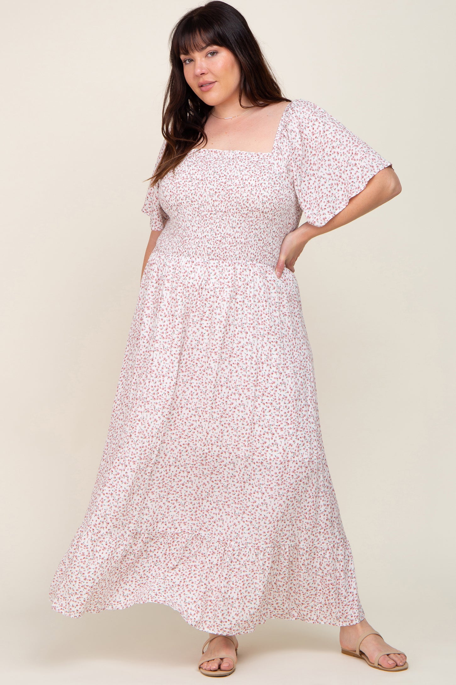 woman wearing a white and pink floral smocked maternity maxi dress with flutter sleeves and square neckline