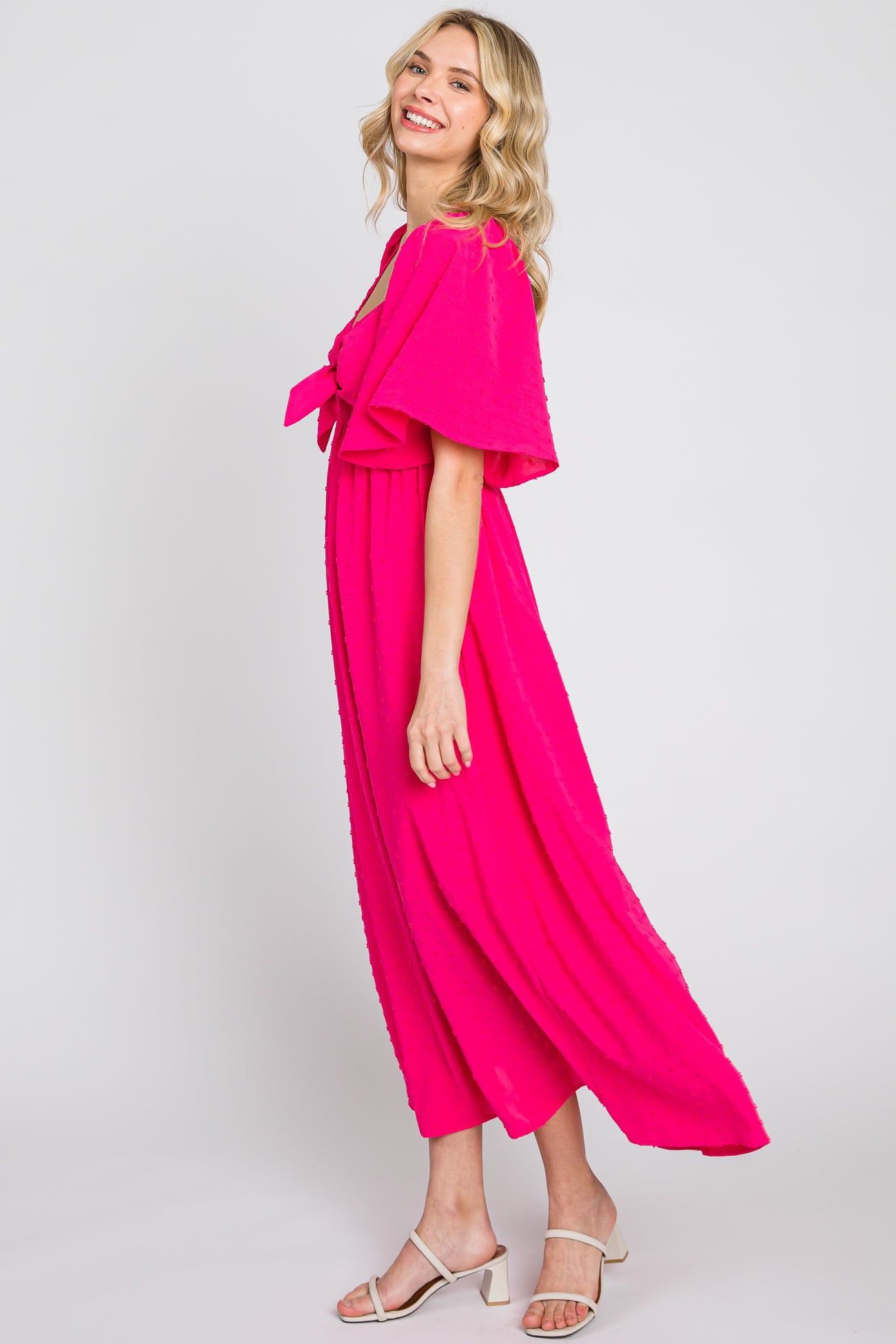woman wearing a bright pink maxi dress with short flutter sleeves and a tie-front detail