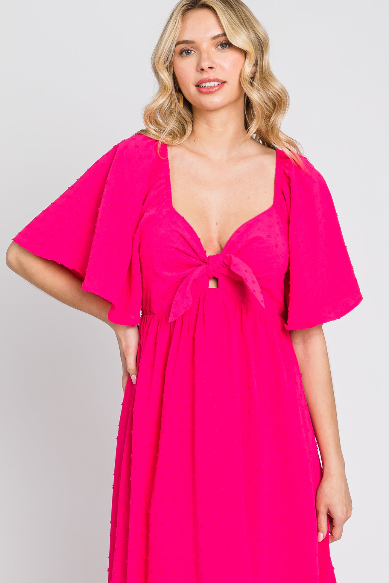 woman wearing a hot pink dress with a tie front and flutter sleeves