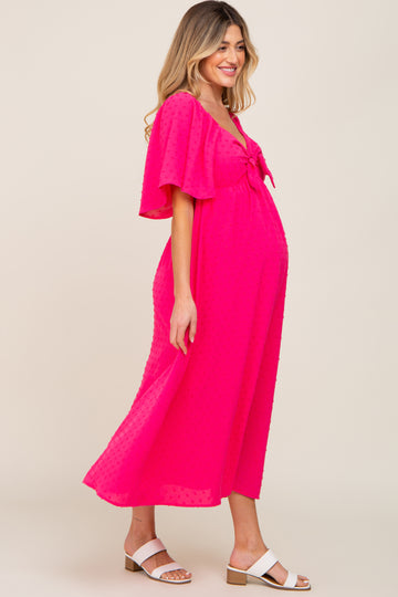 woman wearing a bright pink maternity dress with flutter sleeves and a tie front, showcasing her baby bump