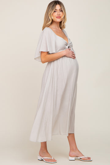 woman wearing a light gray maternity wrap dress with a tie detail and a visible baby bump