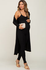 pregnant woman in black ribbed maternity jumpsuit and matching cardigan holding a gold clutch