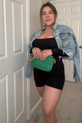 woman wearing a black maternity bodysuit with a denim jacket and holding a green handbag, showcasing a baby bump