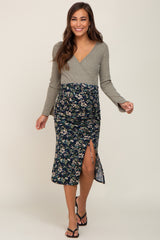 woman wearing a gray long sleeve maternity wrap dress with a floral patterned skirt and a side slit, showing her baby bump