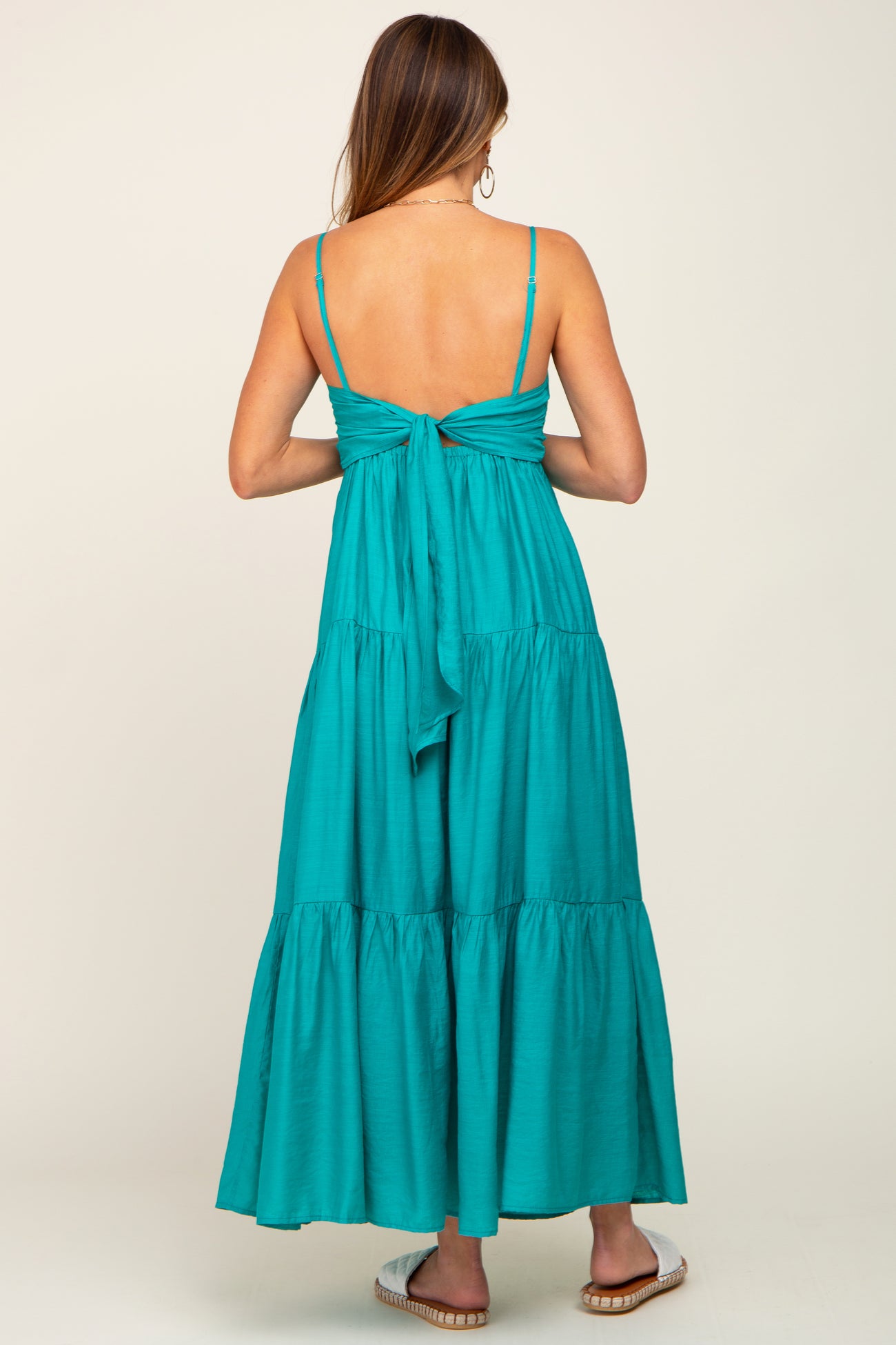 woman wearing a turquoise maxi dress with a tie-back detail and tiered skirt
