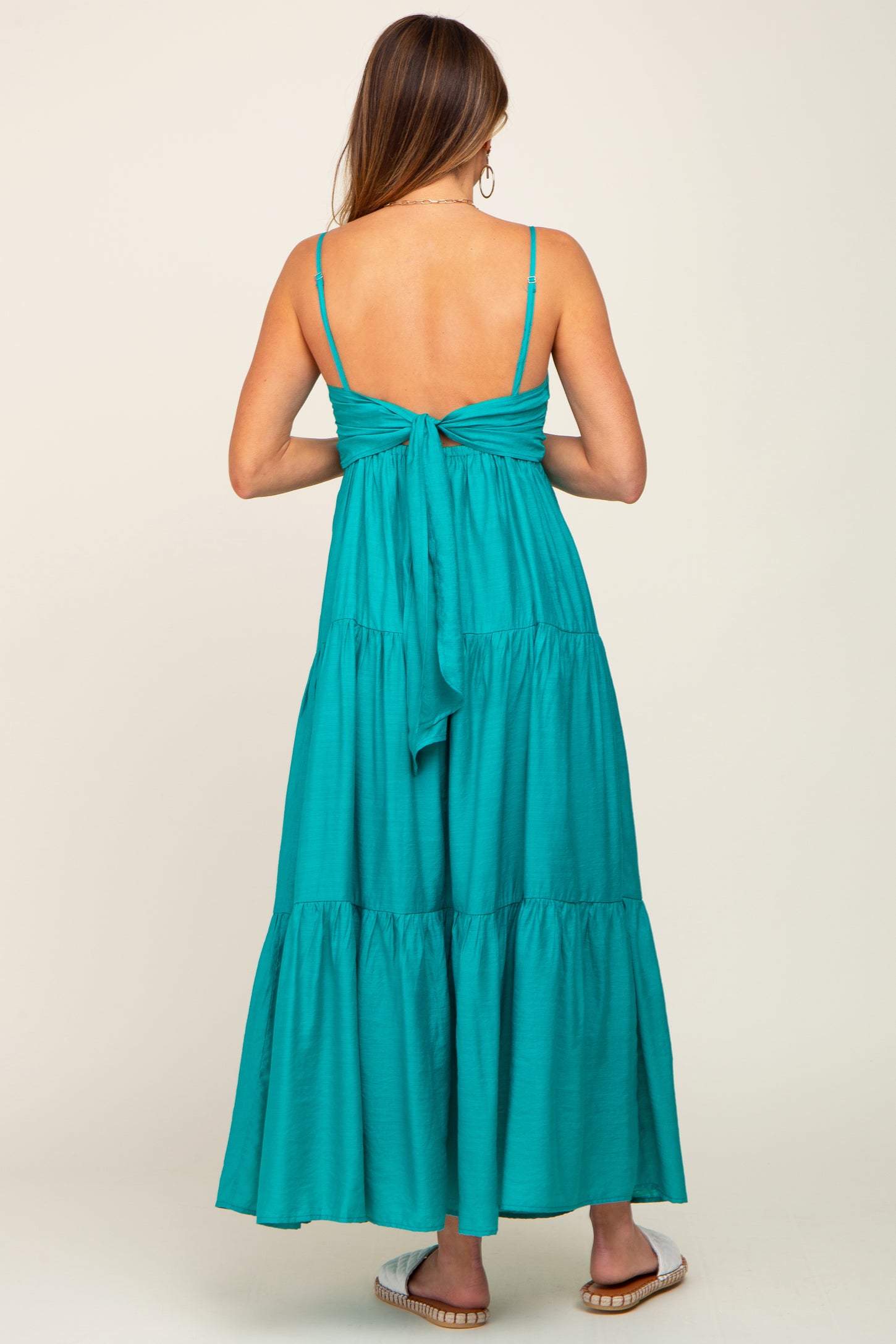 woman wearing a turquoise maxi dress with a tie-back detail and tiered skirt