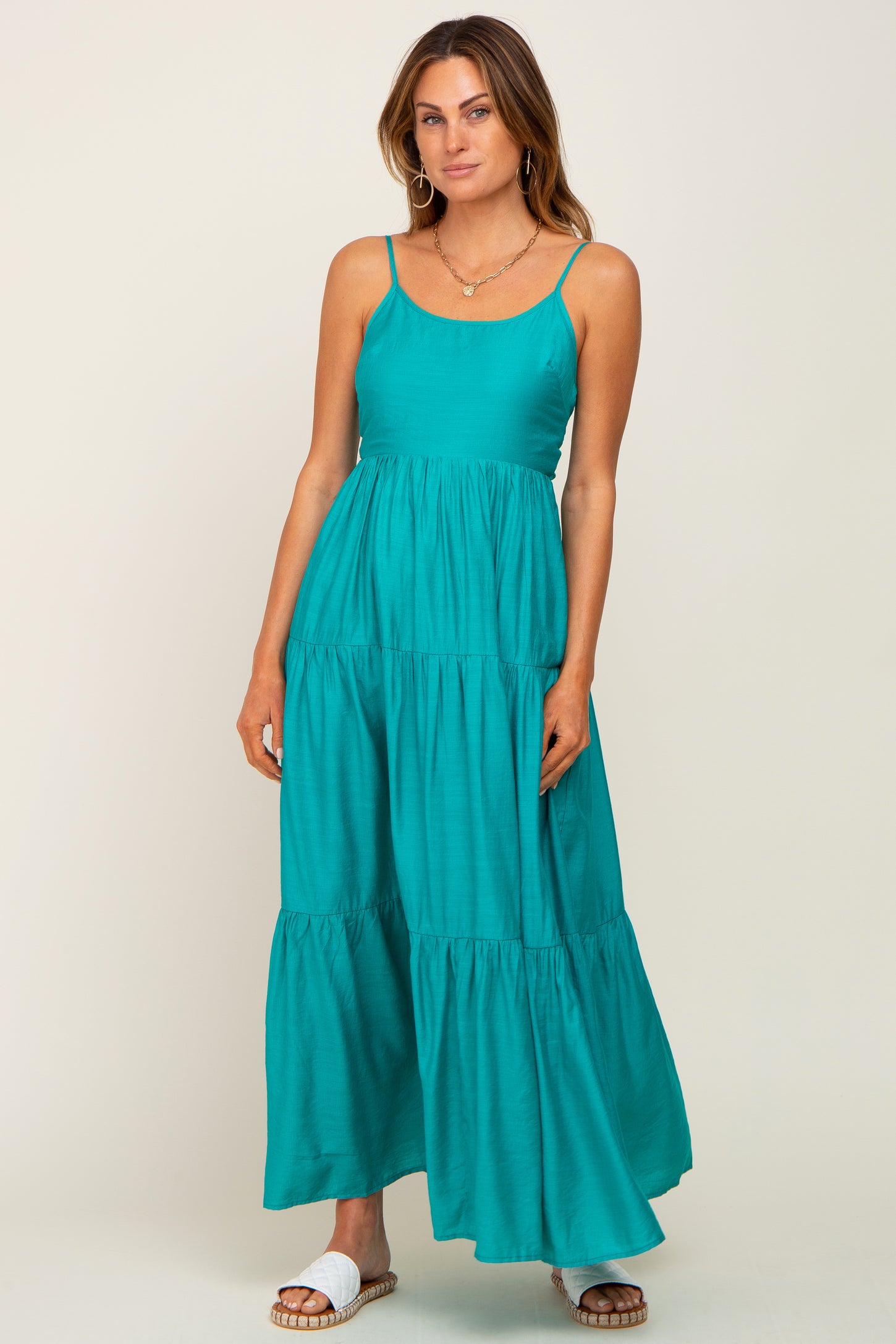 woman wearing a teal sleeveless maxi dress with tiered layers and a relaxed fit