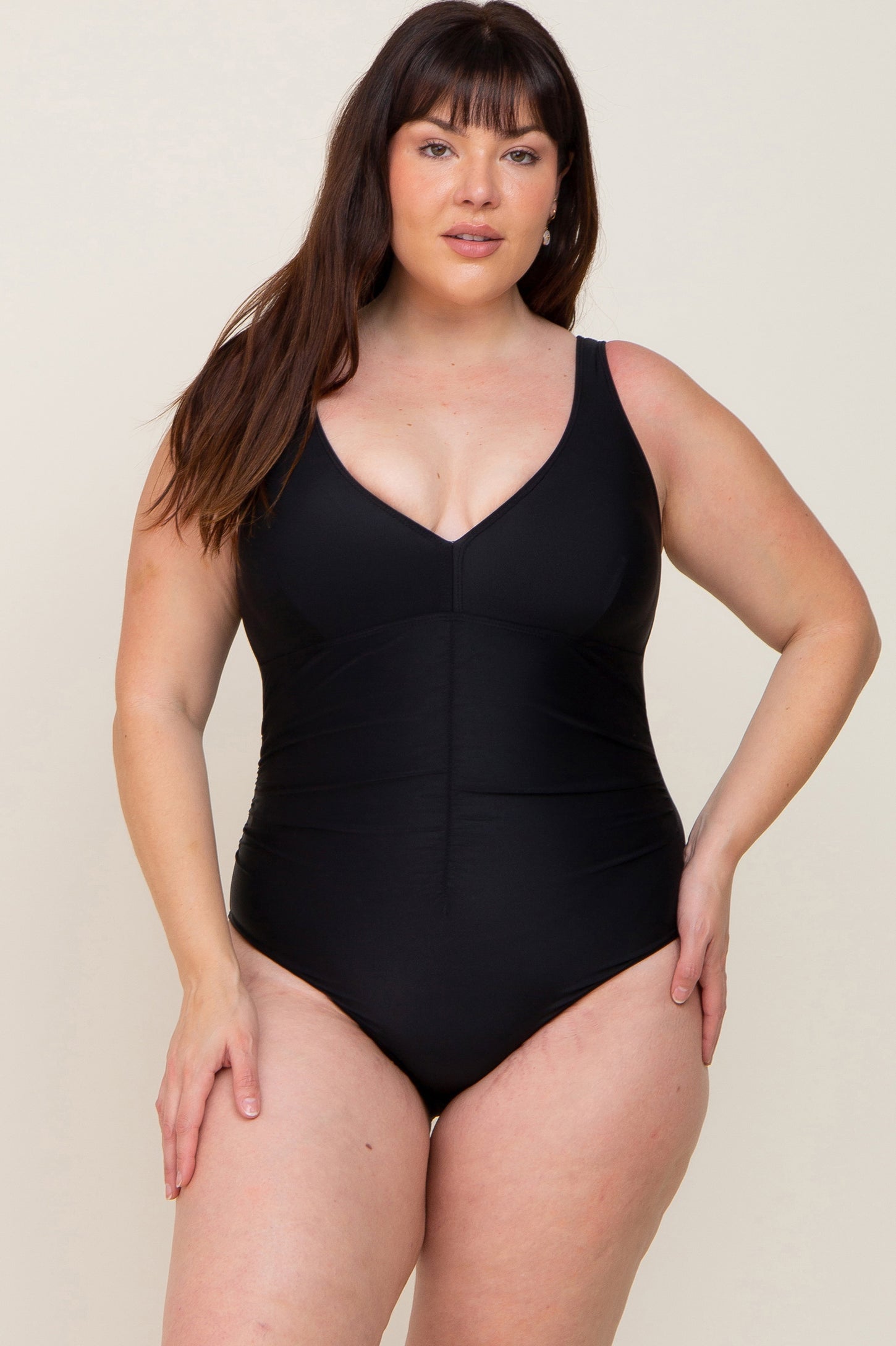plus size woman wearing a black one-piece swimsuit with a v-neckline and ruched bodice