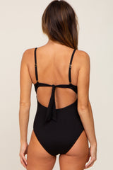 woman wearing a black ribbed one-piece swimsuit with a back tie and cutout detail