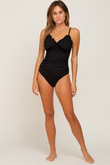 woman wearing a black ribbed one-piece swimsuit with lace trim and adjustable straps