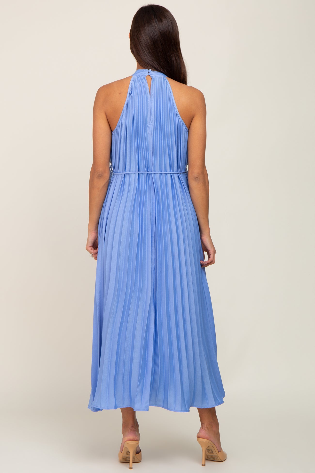 woman wearing a light blue pleated maternity dress with a halter neck and keyhole back detail