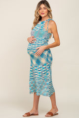 woman wearing a multi-colored patterned maternity dress and holding her baby bump