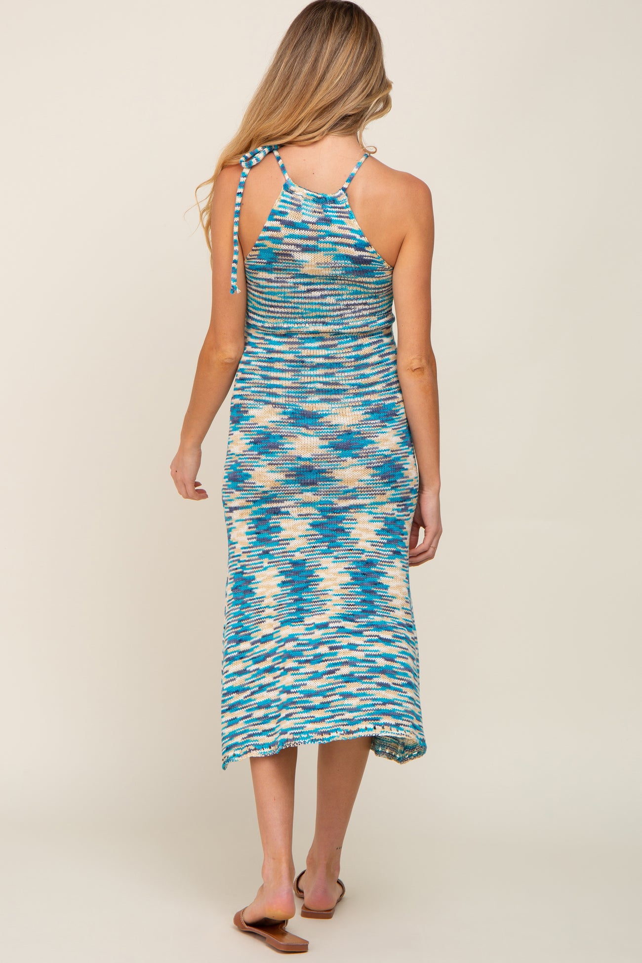 woman wearing a multicolored knit maternity maxi dress with a halter neck and open back design