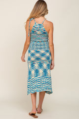 woman wearing a multicolored knit maternity maxi dress with a halter neck and open back design
