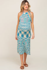 woman wearing a multicolored striped maternity dress with a halter neckline and tie details, showcasing her baby bump