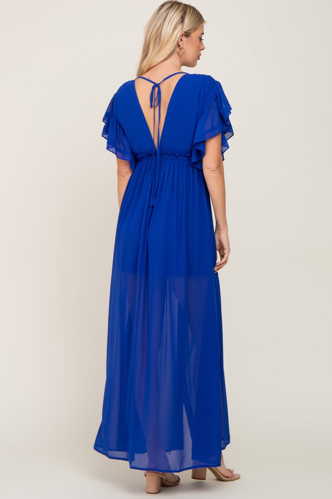 woman wearing a blue maxi dress with ruffled sleeves and an open back, viewed from the back