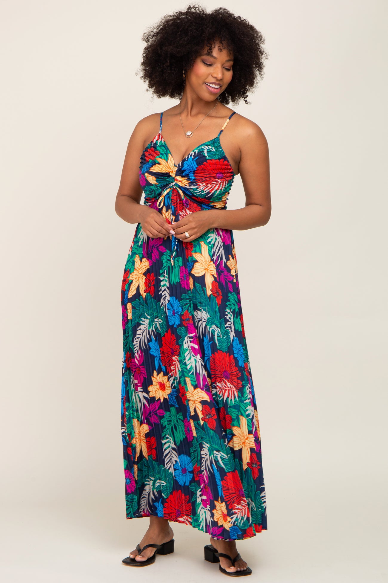 woman wearing a colorful floral print maxi dress with a knotted front and spaghetti straps