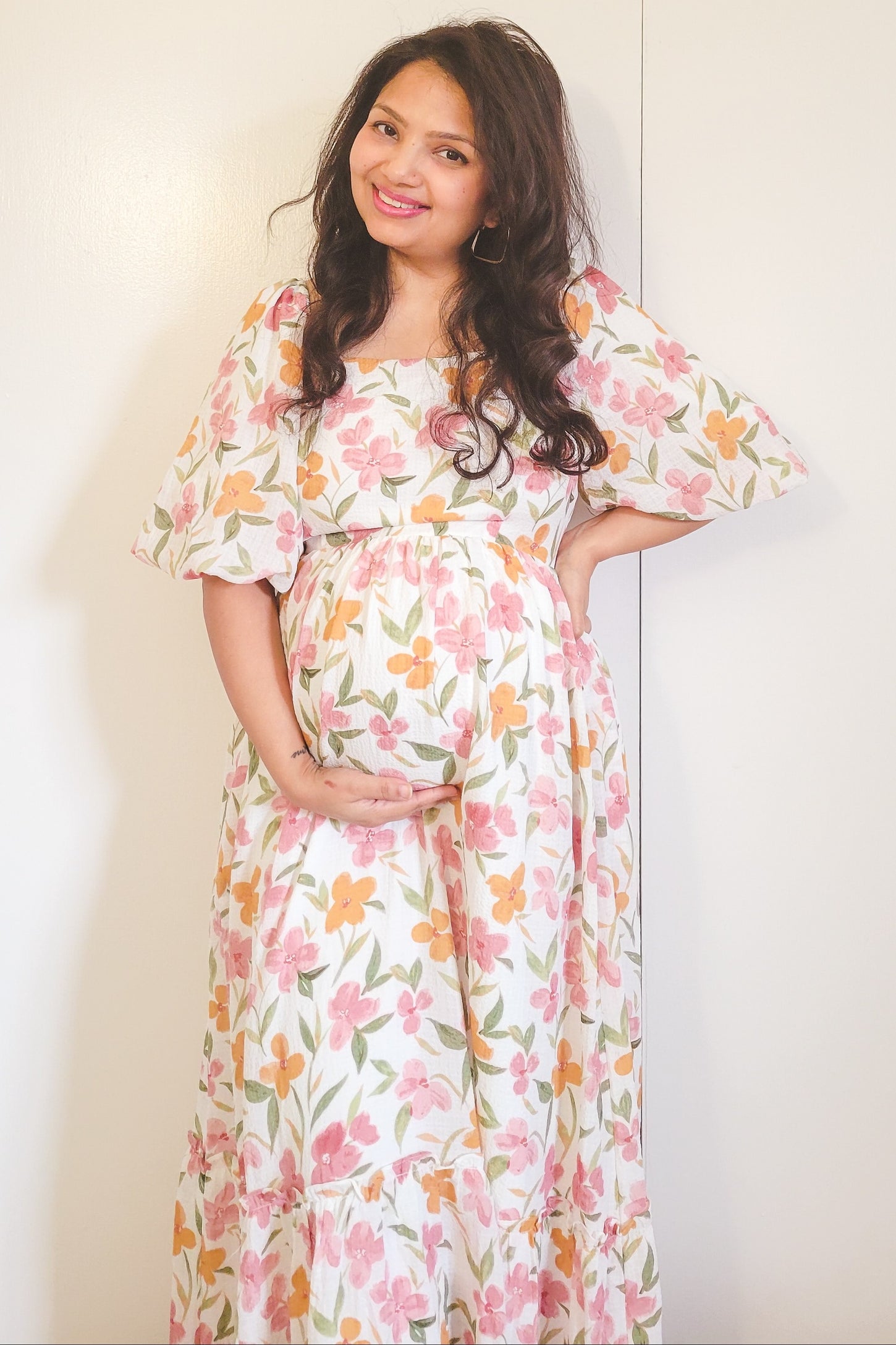 woman wearing a floral maternity maxi dress and holding her baby bump