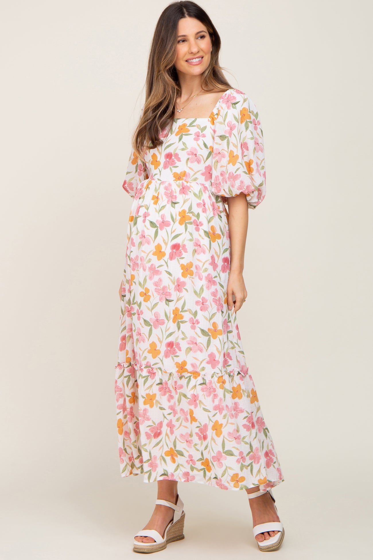 woman wearing a floral print maternity maxi dress with puff sleeves and a square neckline, showing her baby bump