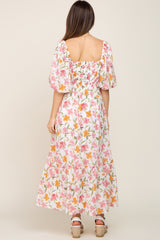 woman wearing a floral maternity maxi dress with puff sleeves and a smocked back, showcasing a baby bump