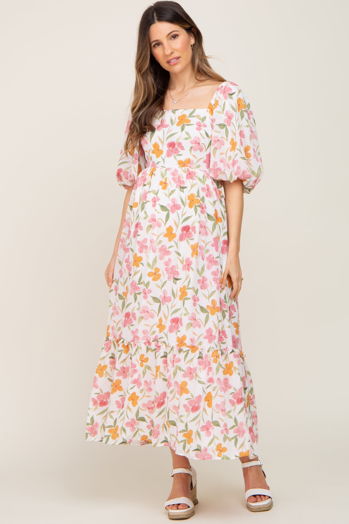 woman wearing a floral print maternity maxi dress with puff sleeves and a tiered skirt, showcasing her baby bump