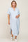 pregnant woman wearing light blue short sleeve button down maternity midi dress and white sneakers