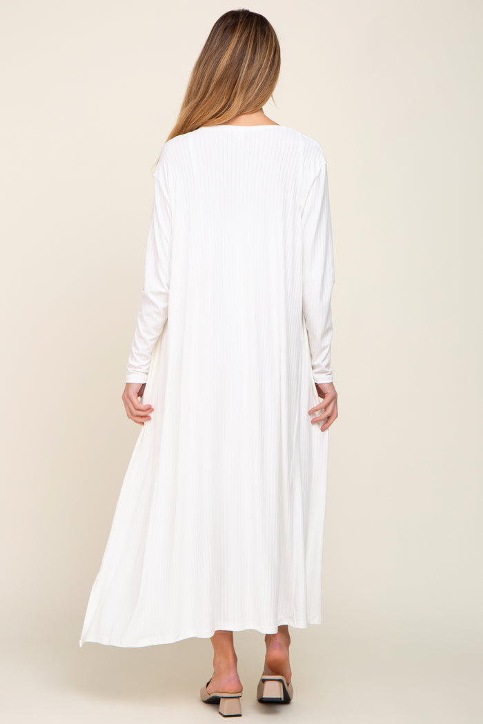 woman wearing a long white ribbed maternity dress with long sleeves, seen from the back