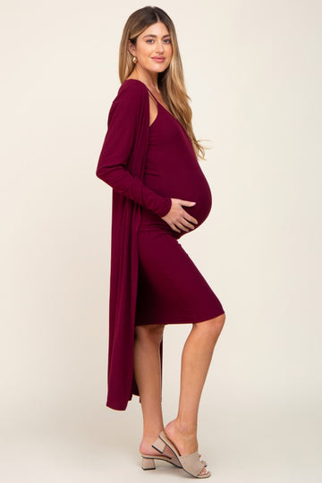 woman wearing a burgundy maternity dress with a long cardigan, showcasing her baby bump