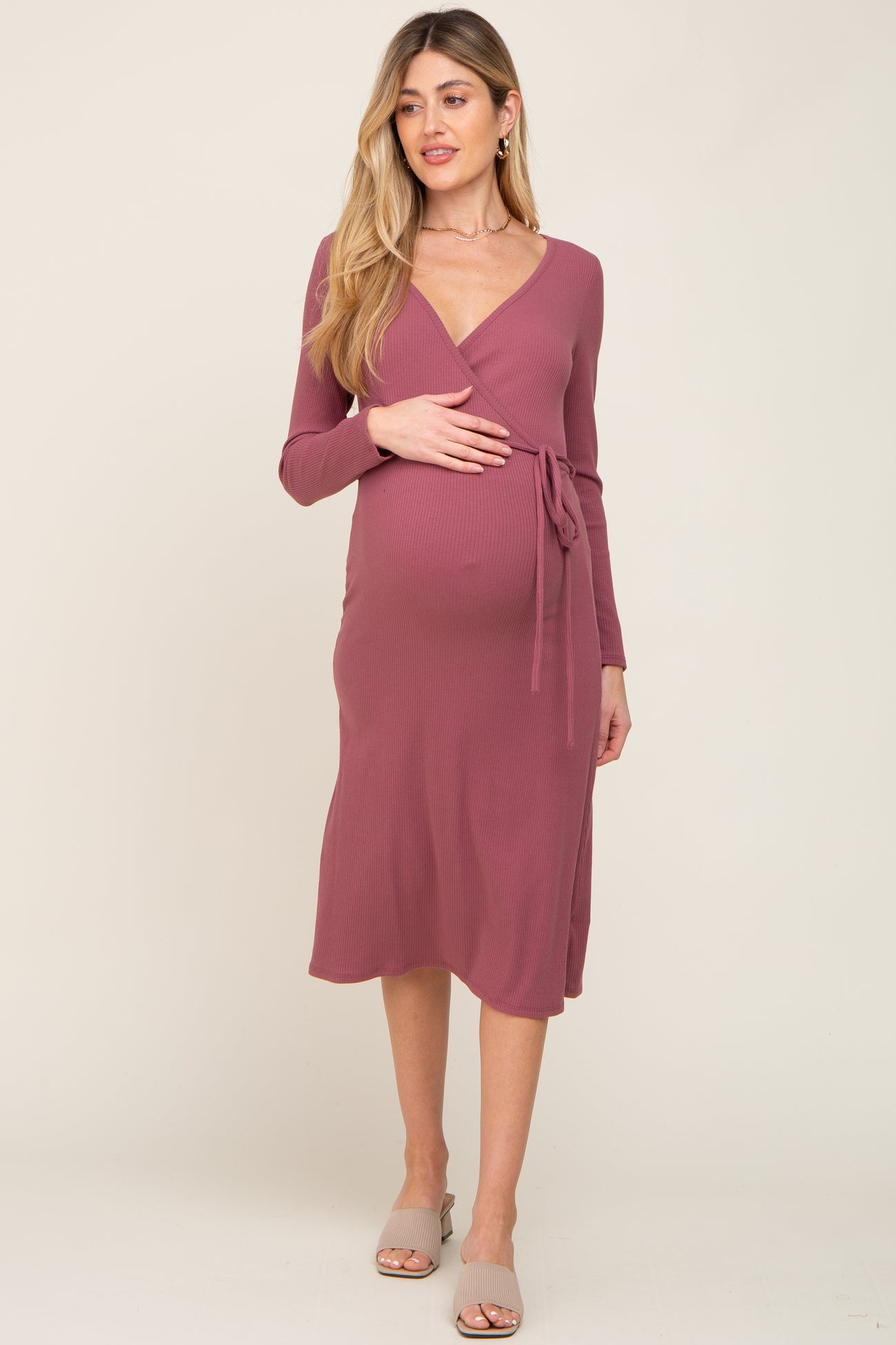 woman wearing a mauve long sleeve wrap maternity dress with a tie waist and visible baby bump