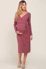woman wearing a mauve long sleeve maternity wrap dress with a tie at the waist, showcasing her baby bump