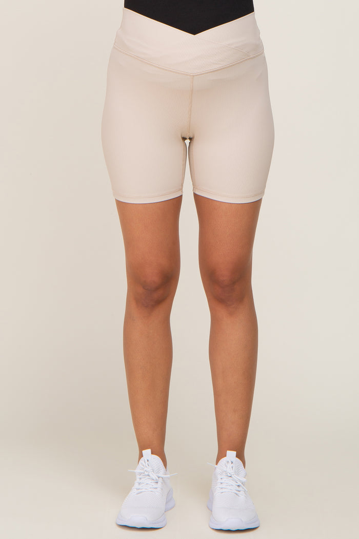 woman wearing beige maternity cycling shorts with a supportive waistband and paired with white athletic shoes
