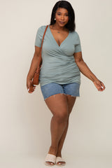 plus size woman in sage green surplice top and denim shorts with brown crossbody bag