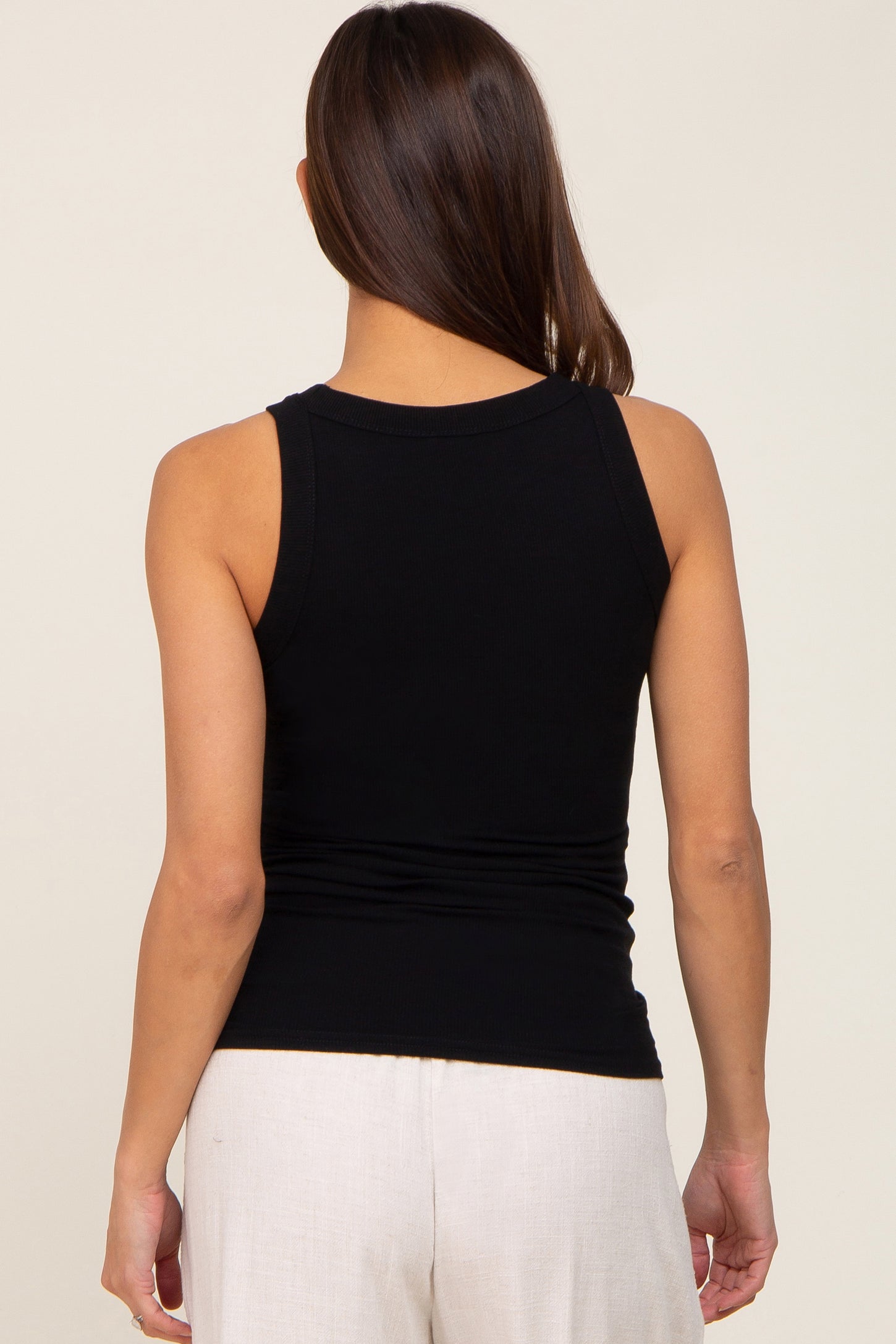 woman wearing a black maternity tank top, view from the back showing ruching details at the waist