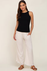woman wearing a black sleeveless maternity top and cream wide-leg pants with pockets