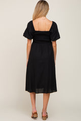 back view of woman wearing black smocked maternity midi dress with puff sleeves and square neckline
