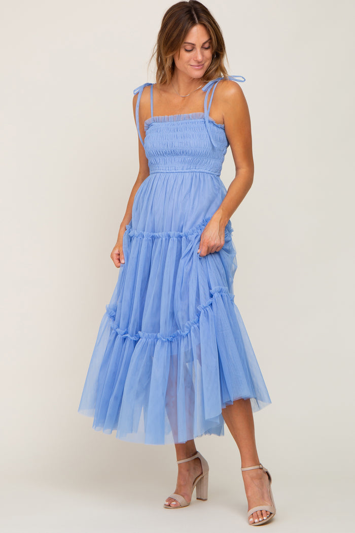 woman wearing a light blue smocked midi dress with tiered tulle skirt and adjustable straps
