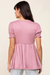 woman wearing a pink puff sleeve top with a smocked waist and flowy hem, showing the back view
